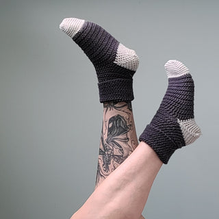 Feet and legs in the air. Feet wearing Hedgehog Crochet Socks.
