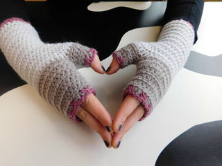 Atelier-fingerless mittens worn against black and white table.