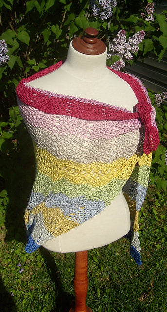 Colorful Bubblegum Crochet Shawl on mannequin in front of lilac tree.
