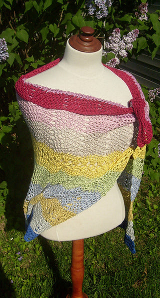 Colorful Bubblegum Crochet Shawl on mannequin in front of lilac tree.