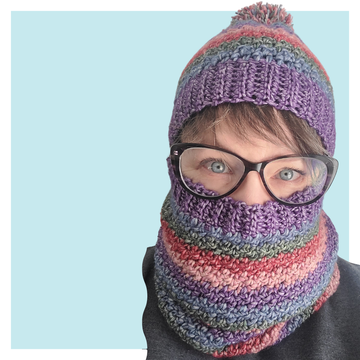 Da Boss Crochet Hat and Cowl worn by woman wearing glasses on turquoise background.