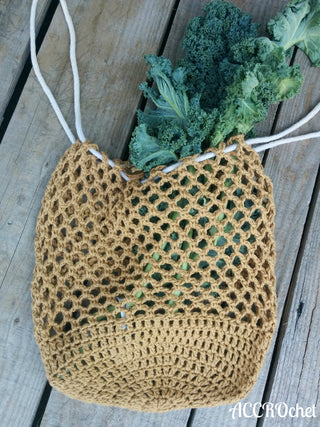 Estelle crochet market bag with kale inside on wood background.