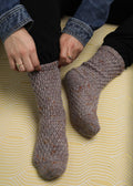 Fireside crochet socks on yellow background.
