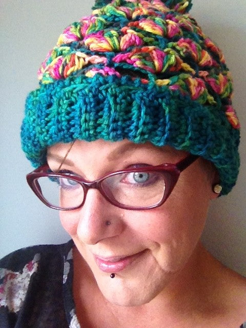 Colorful crochet hat worn by woman wearing glasses.