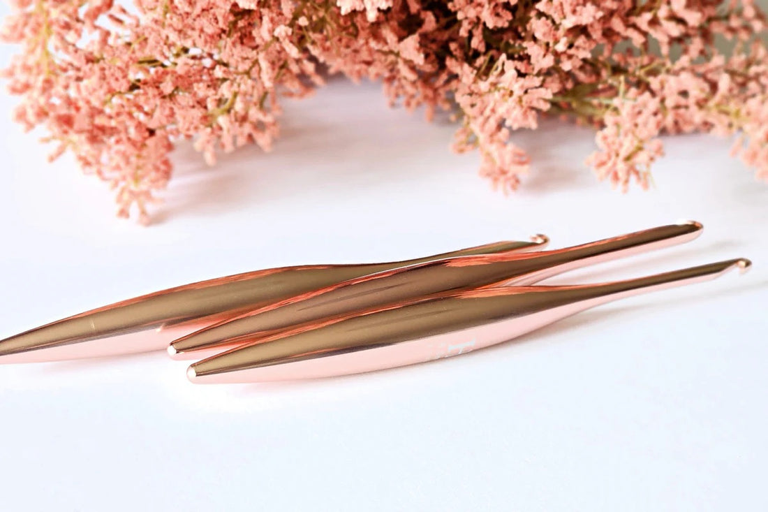 Furls Crochet Hooks Blush Metal  on white background with pink flowers.