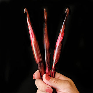 Furls Streamline Hooks Aries in hand on black background.