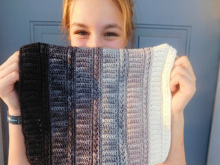 Gradually crochet cowl held in front of teen's face.