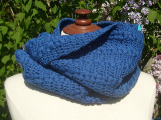 Blue Huguette Crochet Scarf on mannequin in front of lilac tree.