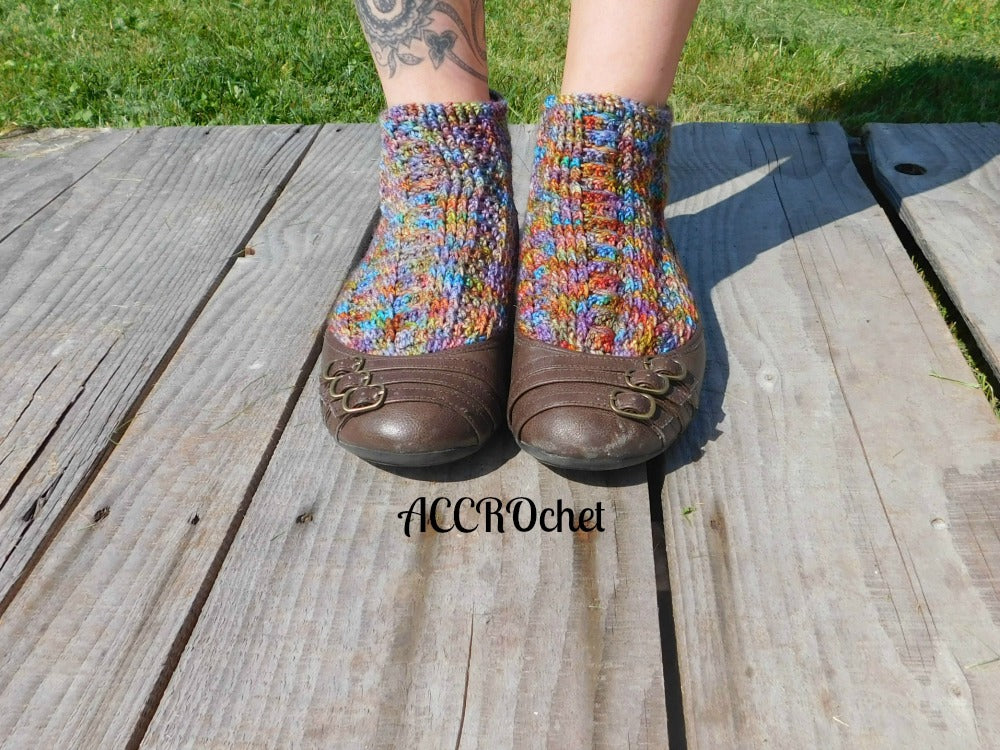 Joséphine crochet socks worn in brown shoes on a patio.