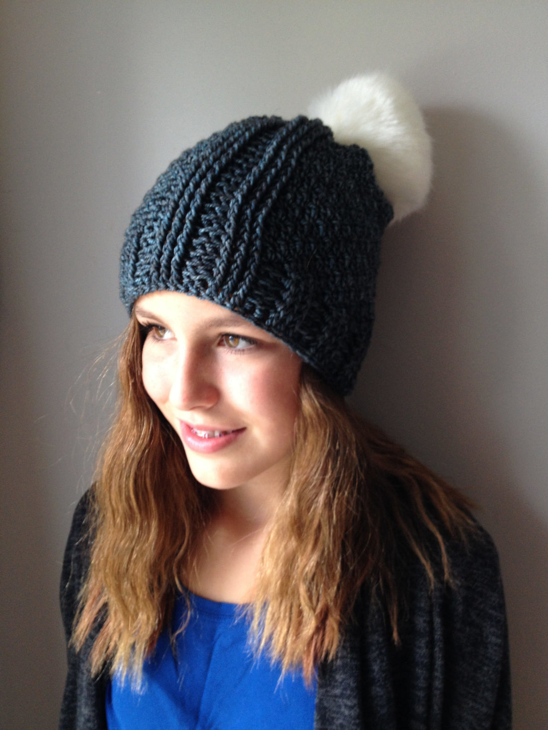Blue Lea Cabled Crochet Hat worn by teen looking to the left.