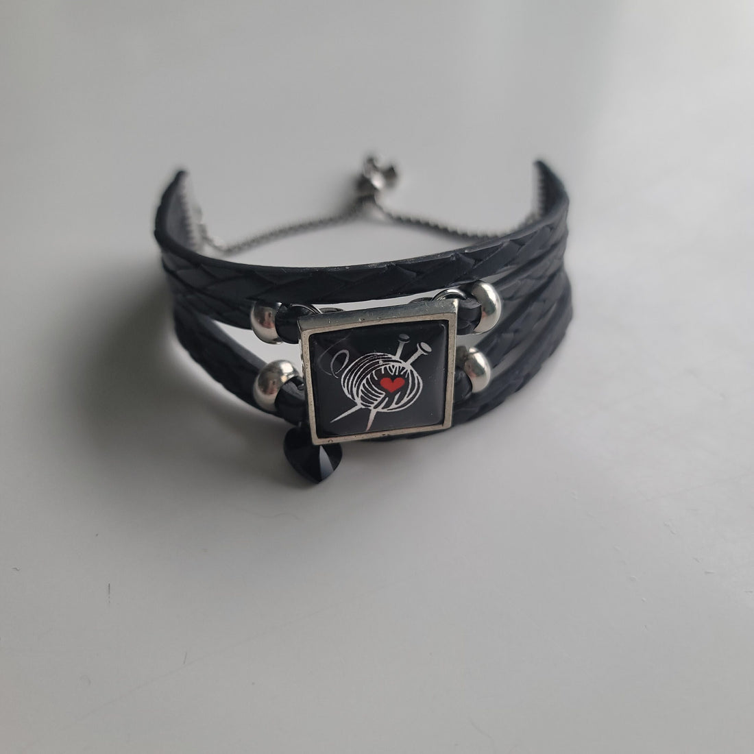 Leather bracelet with yarn and knitting needles printed on stone.