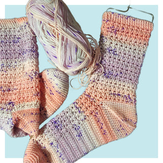 Picture of the Lilac Lemonade crochet socks in pink orange and purple-speckled yarn on turquoise background
