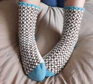 Mint Chocolate Chip crochet socks on beige bedspread.