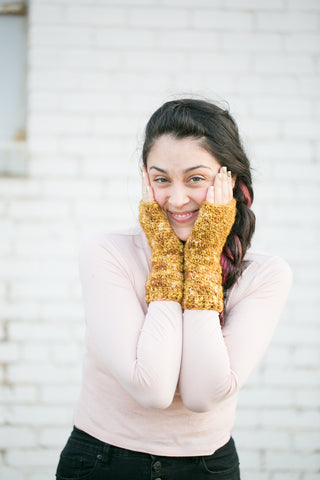 Morning-Sun Fingerless Mittens worn by young woman against a white brick wall.