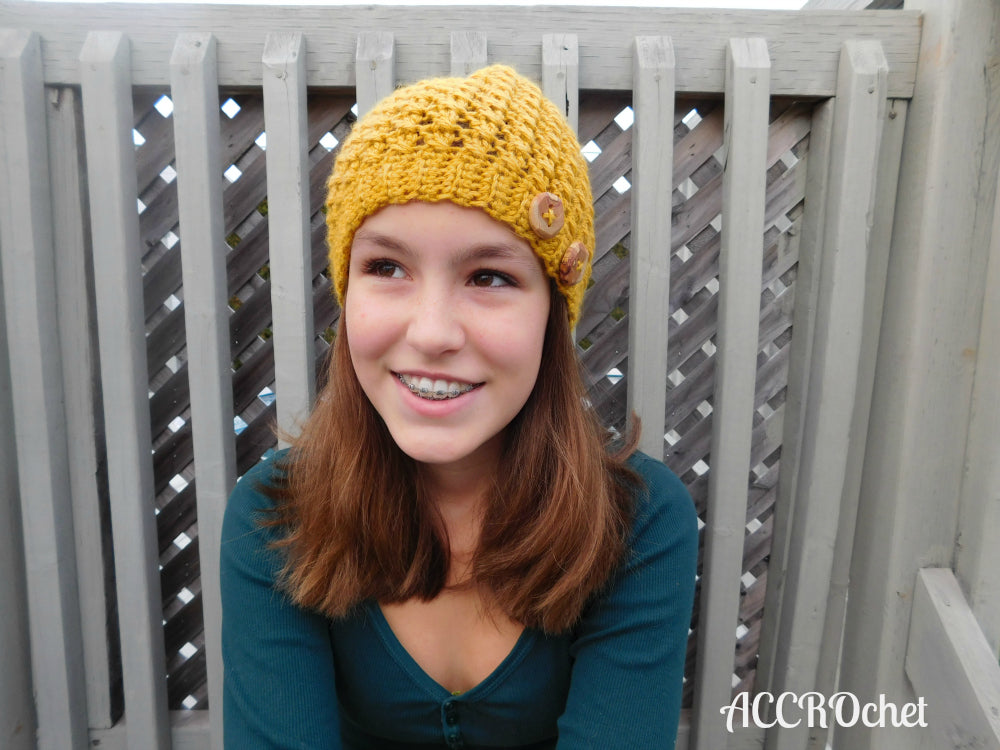 Mustard crochet hat worn by teen on turquoise background.
