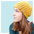 Mustard crochet hat worn by teen on turquoise background.