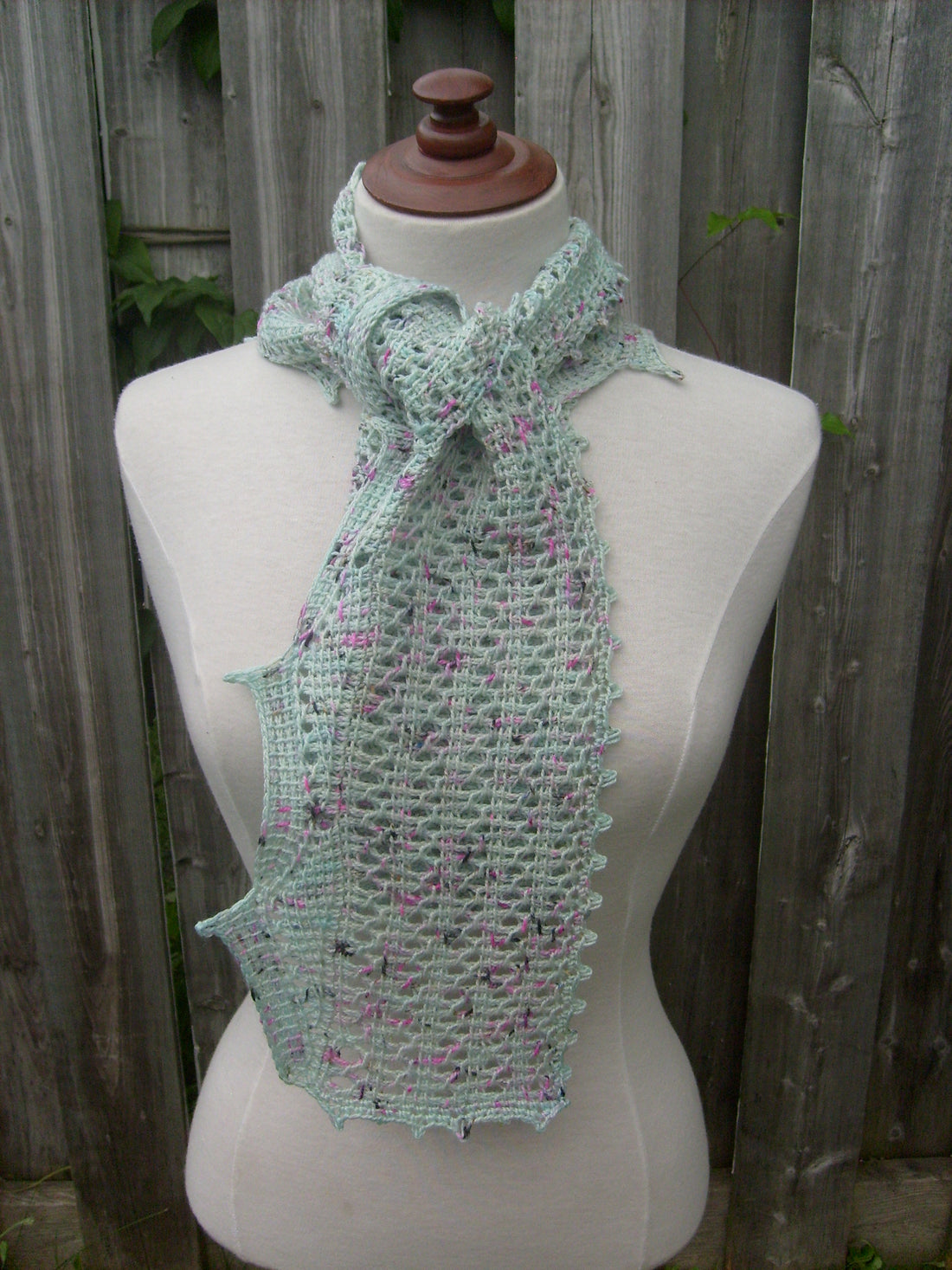 Turquoise Ocean Geometry Tunisian Crochet Scarf on mannequin in front of a fence.