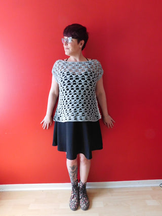 Peek-a-blue crochet top worn by designer in front of a red wall.