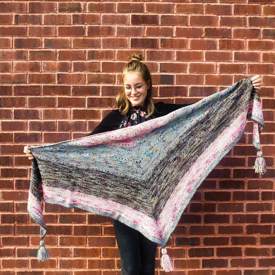 Plumage Crochet Shawl held by teenager against a brick wall.