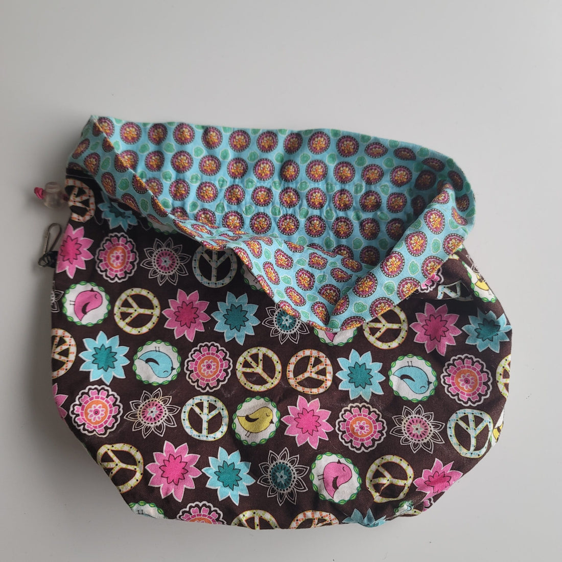 Project bag with peace signs, birds and flowers on brown background.