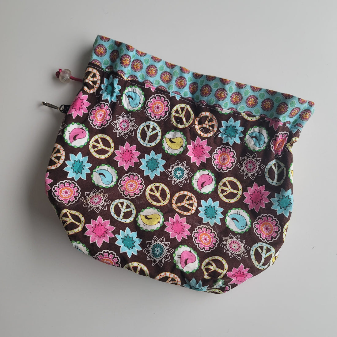 Project bag with peace signs, birds and flowers on brown background.