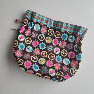 Project bag with peace signs, birds and flowers on brown background.