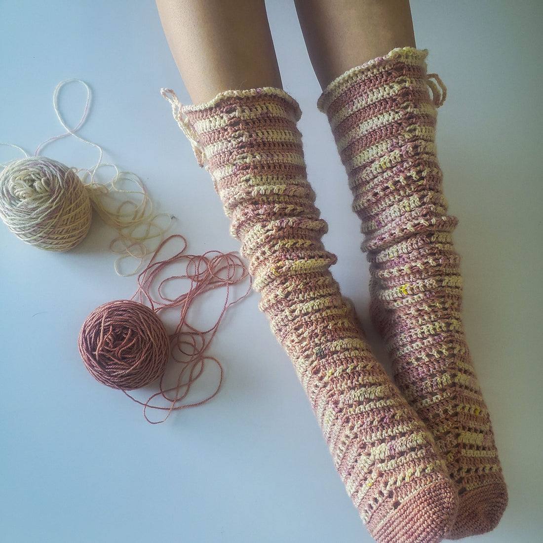 Romance Crochet Socks worn against white background with 2 balls of yarn on the side.