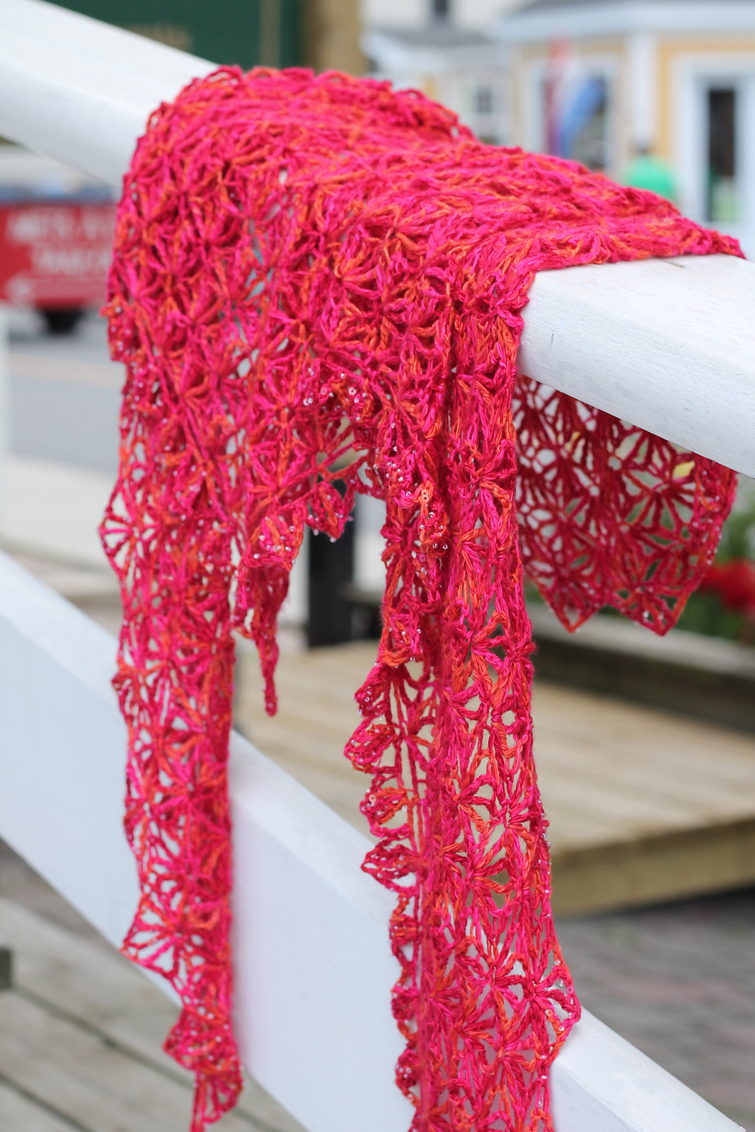 Red Sorbet crochet shawl on white bannister.