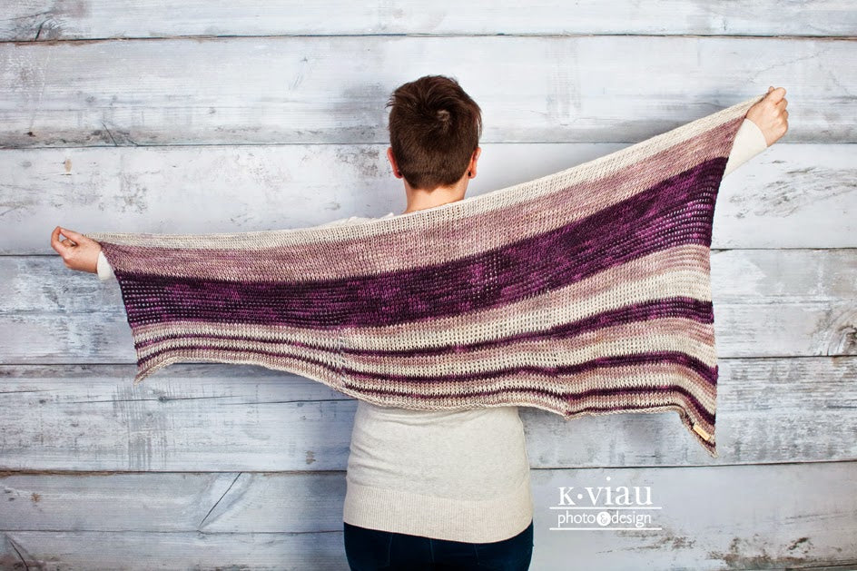 Shades of purple Theoretically Tunisian Crochet Shawl worn by woman facing white background.
