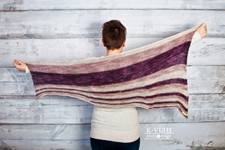 Shades of purple Theoretically Tunisian Crochet Shawl worn by woman facing white background.