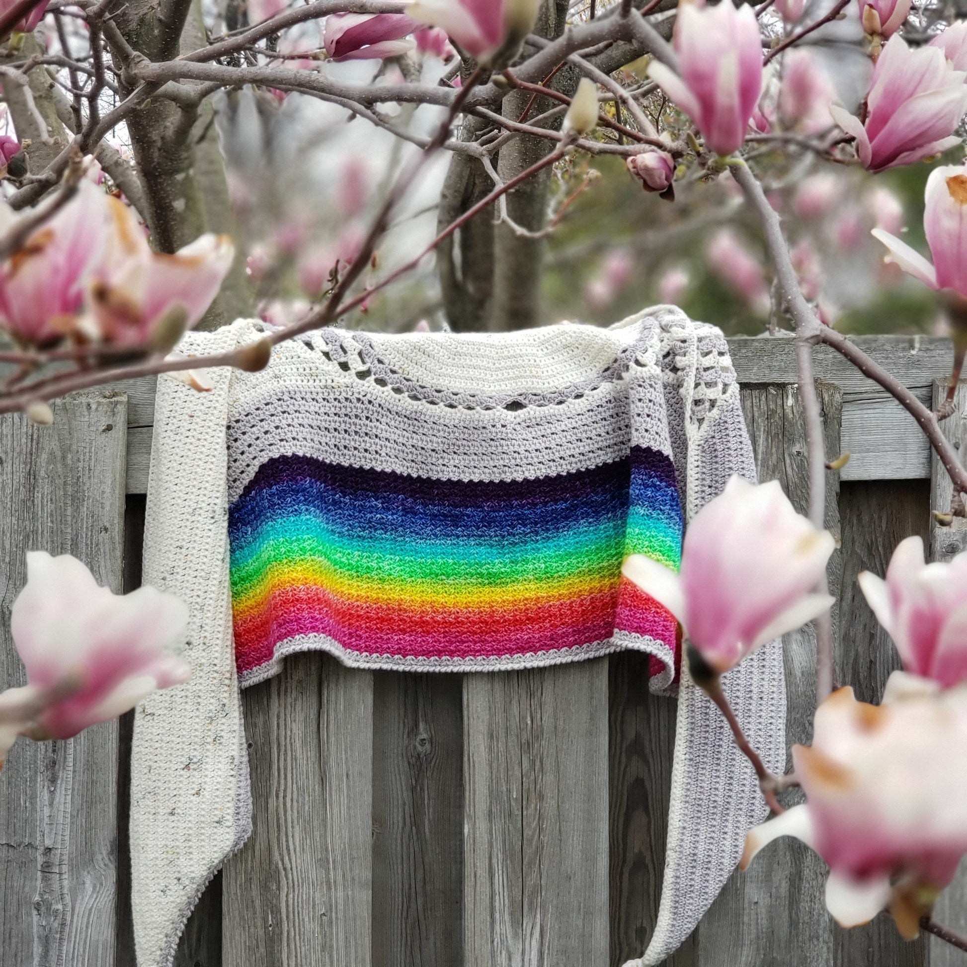 Under-the-rainbow-crochet shawl on fence with magnolia flowers.