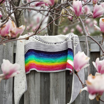 Under-the-rainbow-crochet shawl on fence with magnolia flowers.