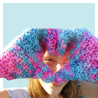 Unicorn crochet mittens worn by teen on turquoise background.