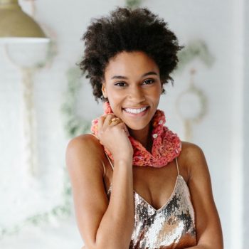 Black woman in sequin top wearing art yarn crochet cowl