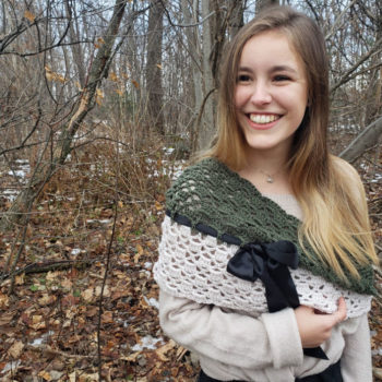 Young woman wearing cream and green crochet shoulder wrap in the woods