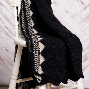 Black and white crochet blanket on white wooden chair