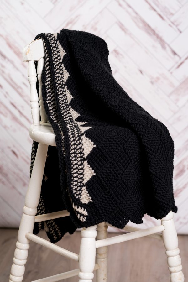 Black and white crochet blanket on white wooden chair