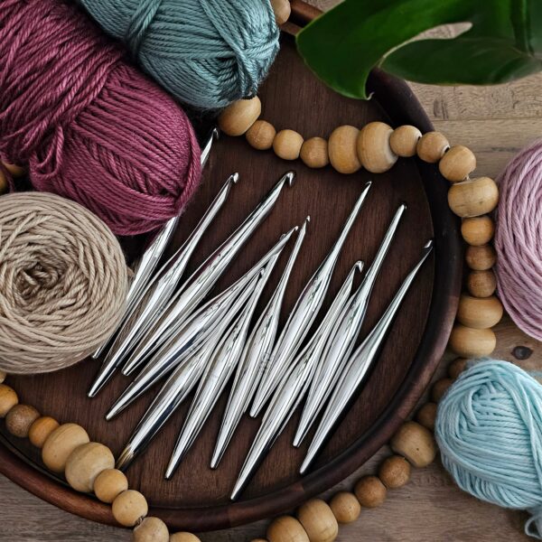 Furls Streamline Metal hooks in a wooden tray, surrounded by balls of yarn